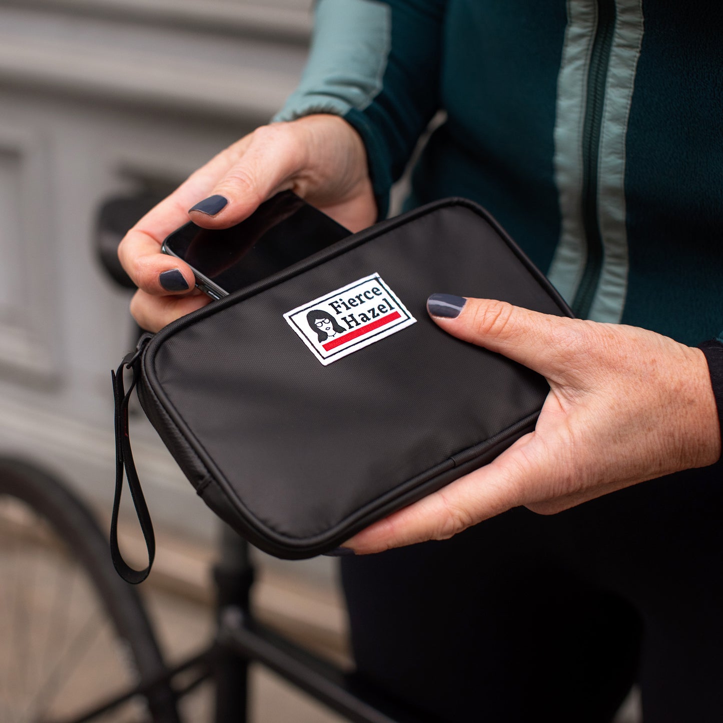 Woman using the Fierce Hazel Ultra Fierce Weatherproof Wallet. Designed for cycling, gravel rides, bikepacking, travel, and every day wallet. Phone case and eco-friendly.