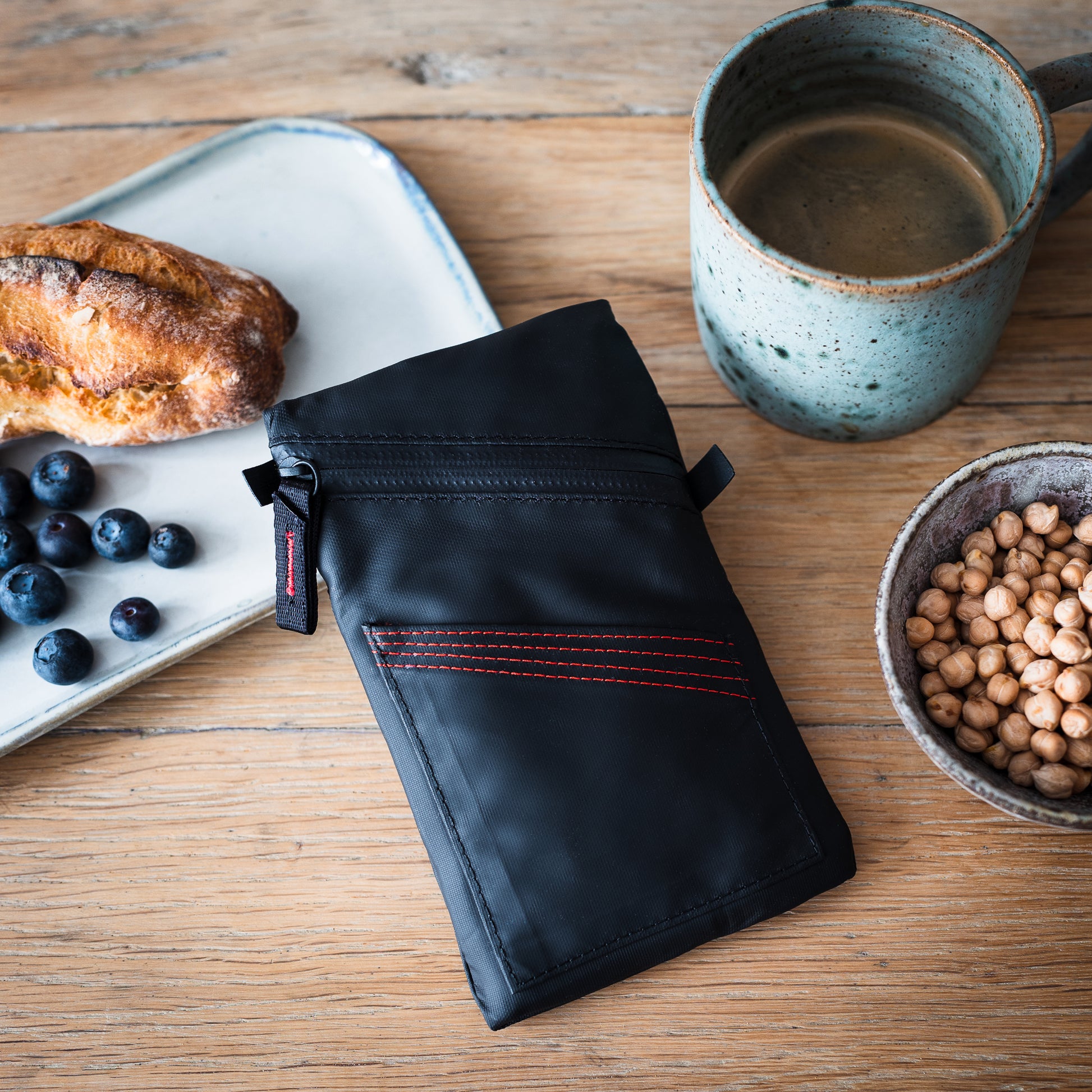 Fierce Hazel Echelon Pouch in Ballistic black. Durable, minimalist wallet on tabletop at coffee shop.