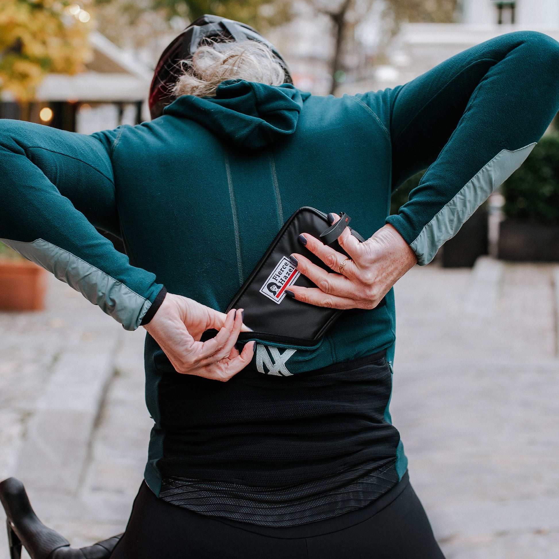 Woman using the Fierce Hazel Ultra Fierce Weatherproof Wallet. Designed for cycling, gravel rides, bikepacking, travel, and every day wallet. Phone case and eco-friendly.
